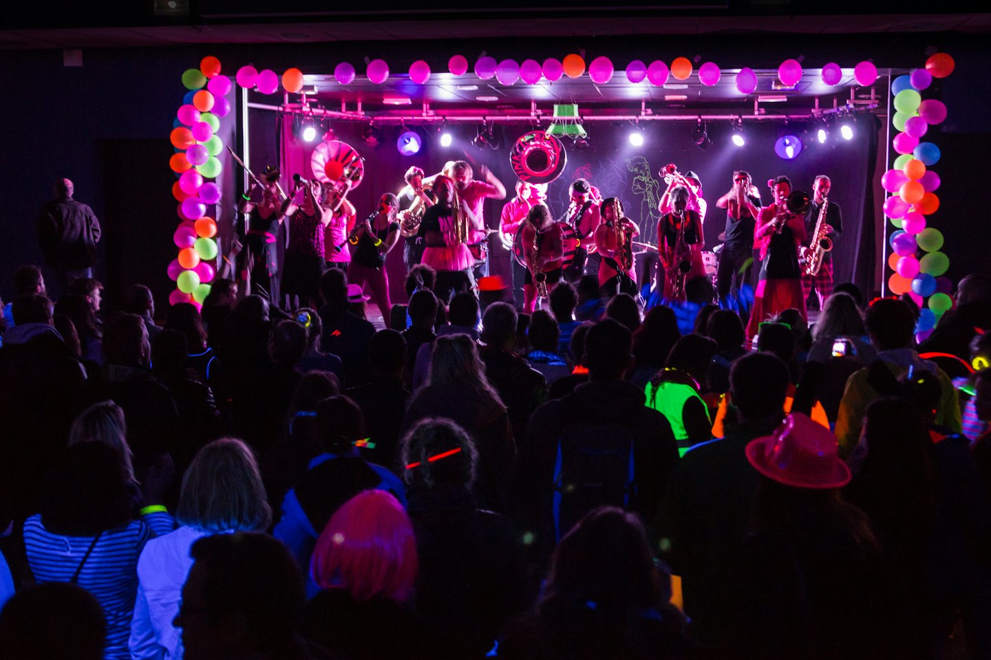 Una band si esibisce sul palco circondata da palloncini al neon.