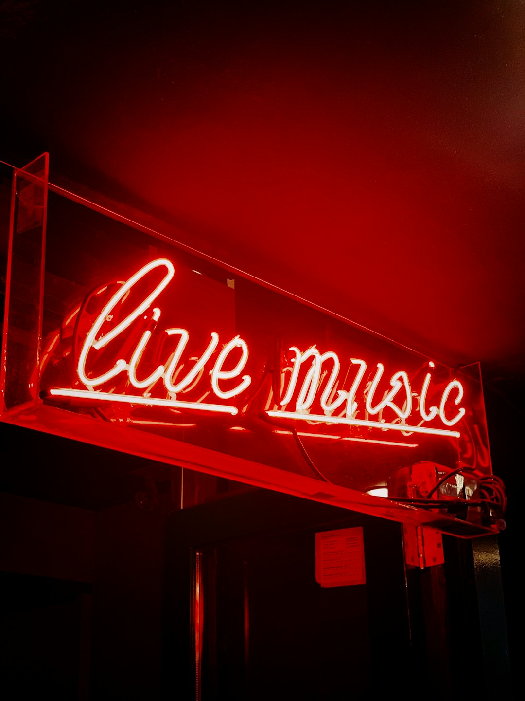 Insegna al neon rossa con la scritta "live music" montata su un muro.