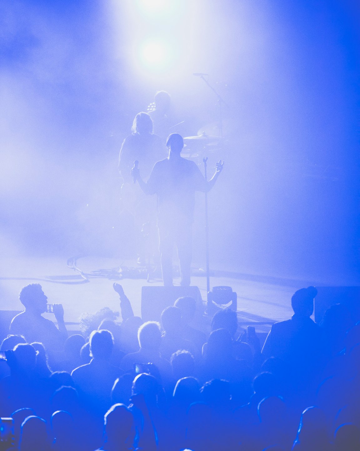 Cantante sul palco con le braccia alzate verso la folla del concerto.