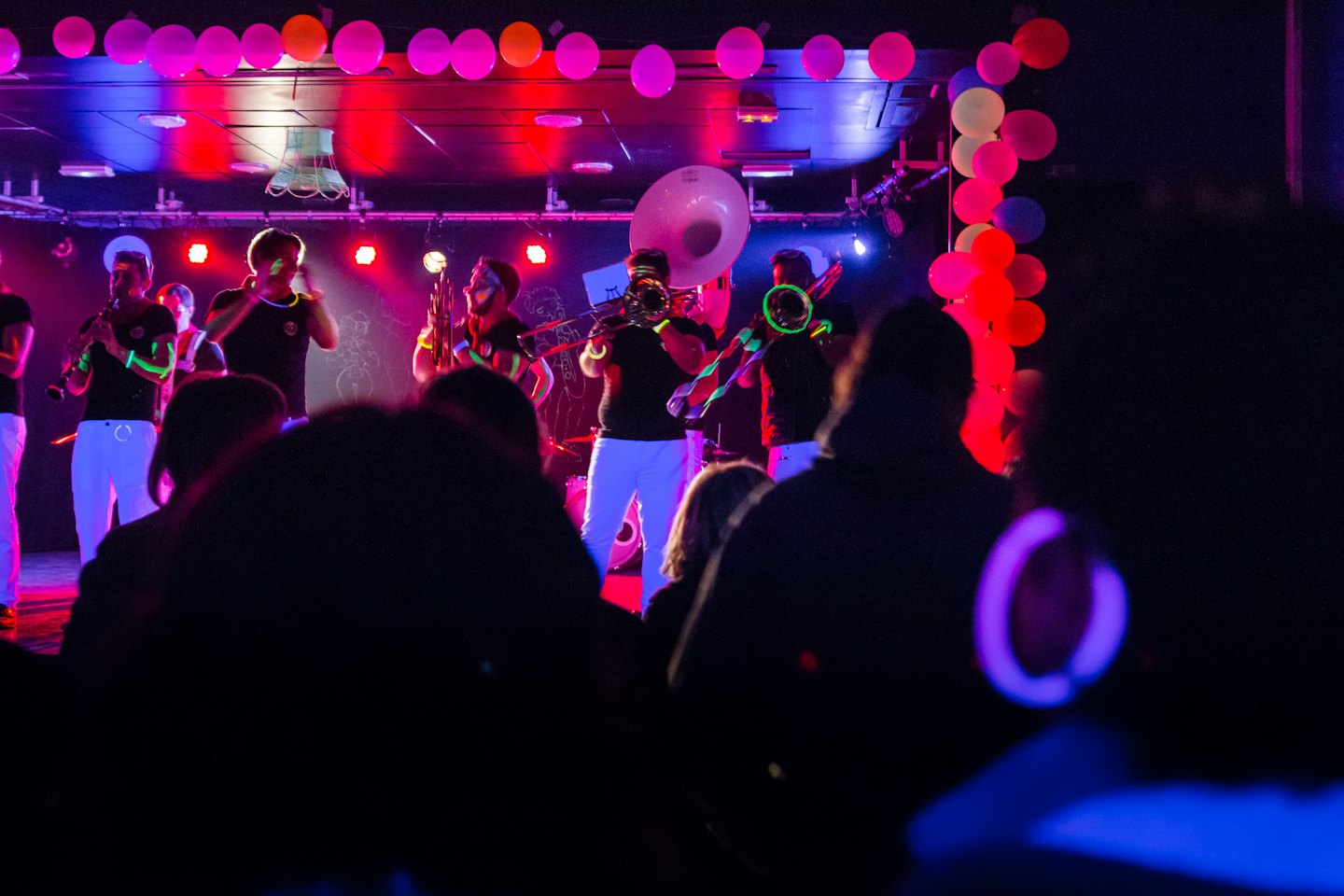 Una band si esibisce sul palco con luci al neon e dettagli fosforescenti.