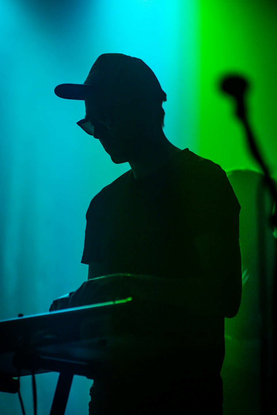 Musicista in silhouette suona una tastiera sintetizzatore sul palco.