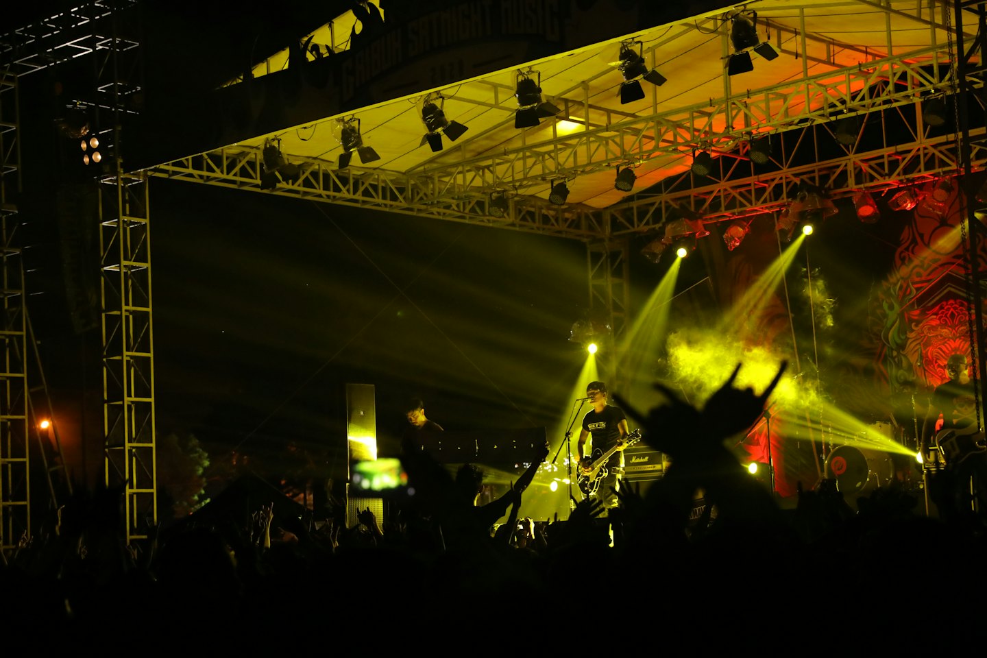 Una band rock dal vivo si esibisce per una folla su un palco all'aperto.